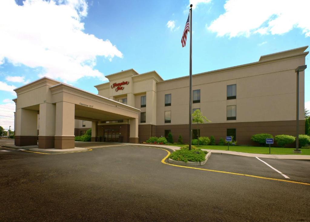 北不伦瑞克Hampton Inn North Brunswick NJ的停车场内悬挂美国国旗的酒店