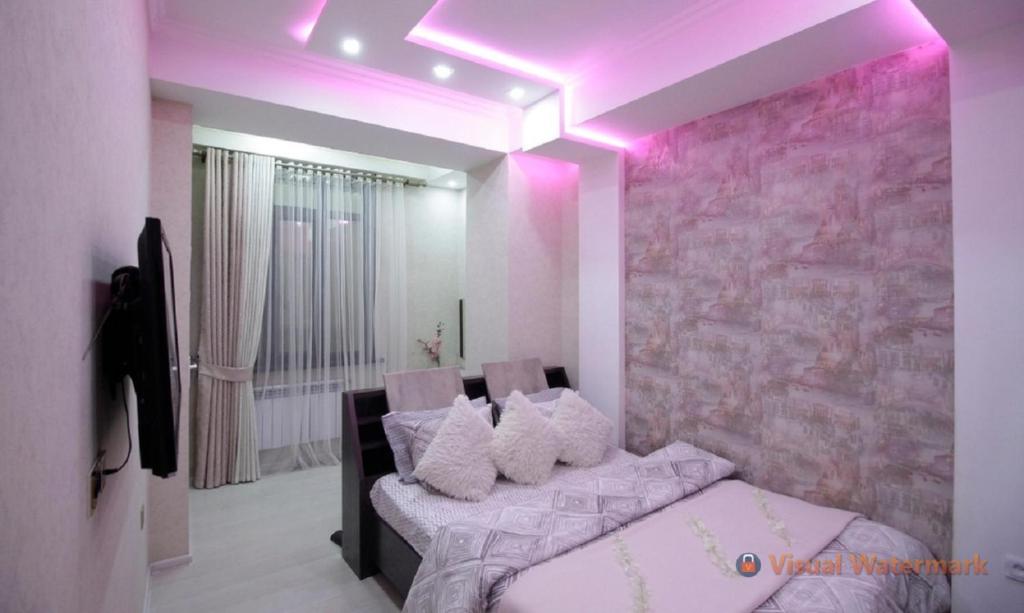 杜尚别Квартира с хорошей энергетикой的卧室配有粉红色的灯光和一张带枕头的床