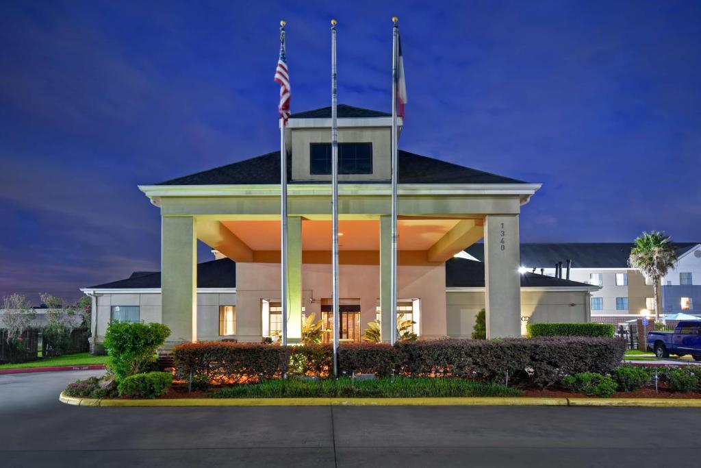 休斯顿休士顿乔治布希洲际机场希尔顿惠庭套房酒店的前面有两面旗帜的建筑