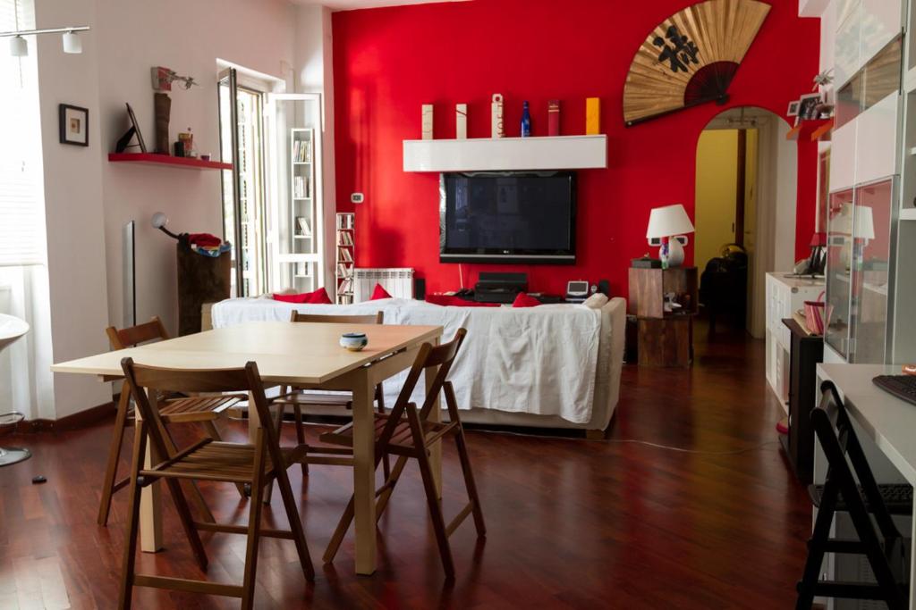 罗马Vacanze Romane con giardino的一间设有桌子和红色墙壁的餐厅