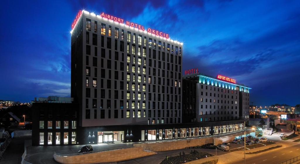 华沙奥克西机场酒店的一座大建筑,上面有灯,晚上