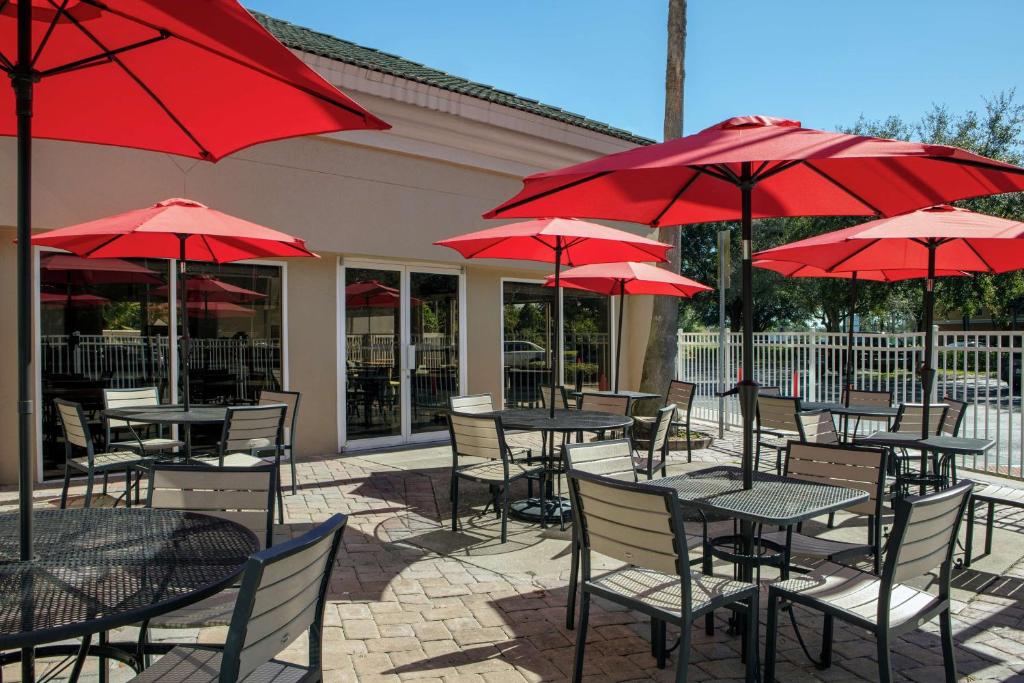 奥兰多博伟湖/奥兰多汉普顿酒店的一组桌椅和红色遮阳伞