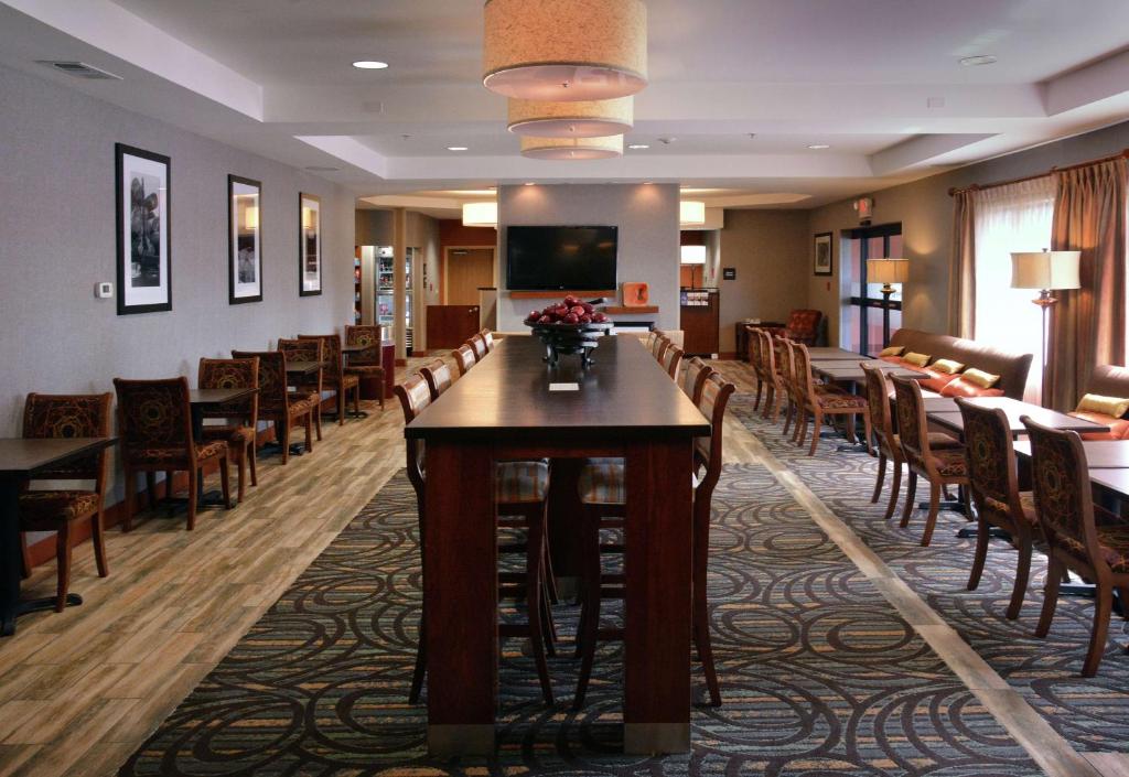 梅德福Hampton Inn Medford的一间带桌椅和电视的用餐室