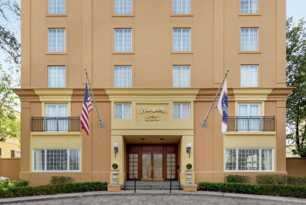 新奥尔良新奥尔良/圣查尔斯大道汉普顿酒店的前面有两面旗帜的建筑