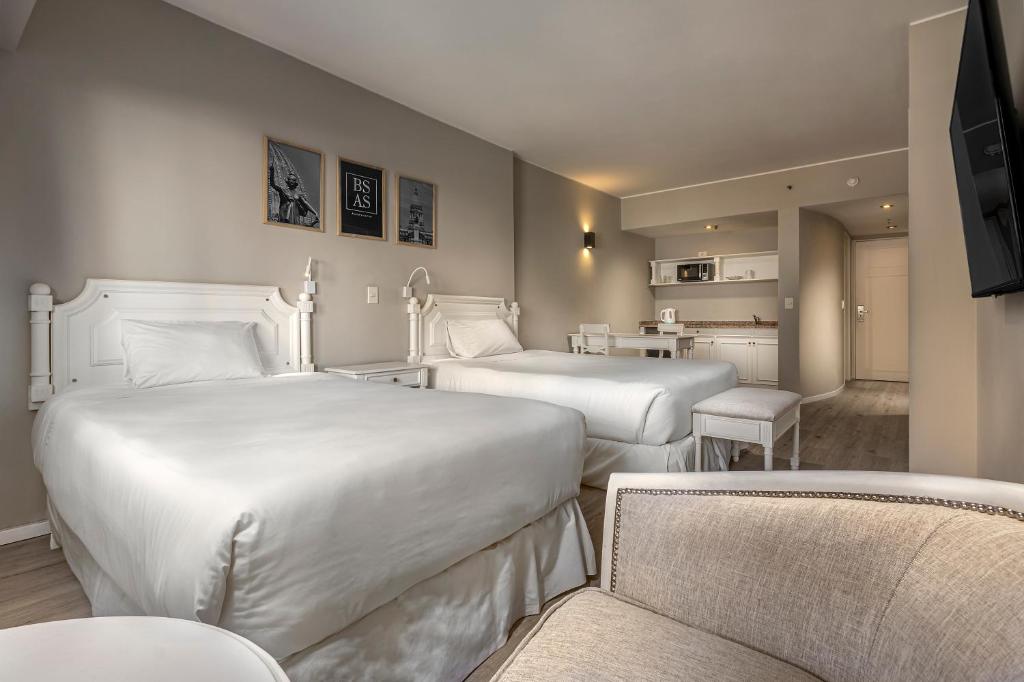 布宜诺斯艾利斯Up América Plaza的酒店客房带两张床和一张桌子以及椅子。