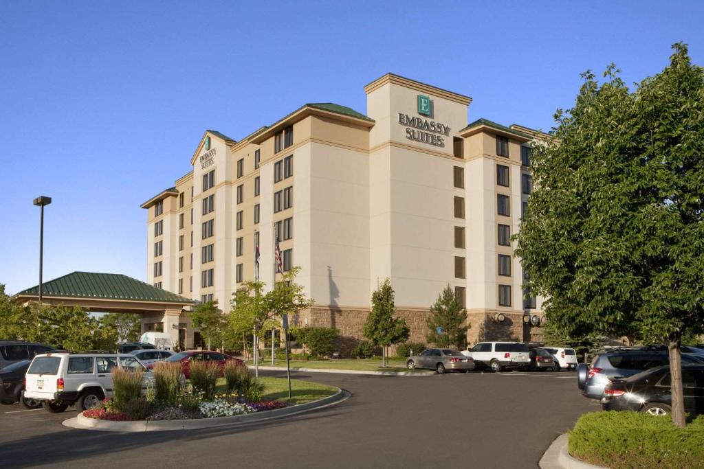 丹佛Embassy Suites by Hilton Denver International Airport的停车场内停放汽车的酒店大楼
