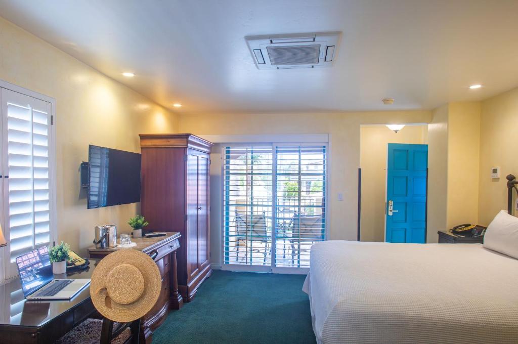 圣巴巴拉Castillo Inn at the Beach的一间带床、书桌和窗户的酒店房间