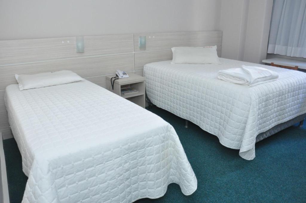 库里提巴Rede Andrade San Martin的配有白色床单的酒店客房内的两张床
