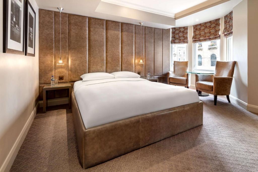 伦敦Radisson Blu Hotel, London Bloomsbury的一间卧室配有一张大床和一张桌子及椅子