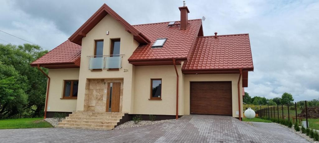 LeszczewekPrzytulisko Leszczewek的一座有红色屋顶和车道的房子