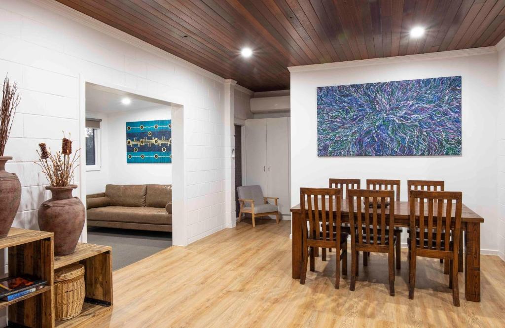 艾利斯斯普林斯4 Bedrooms, 2 Bathrooms in Alice Springs的一间带桌椅和绘画的用餐室
