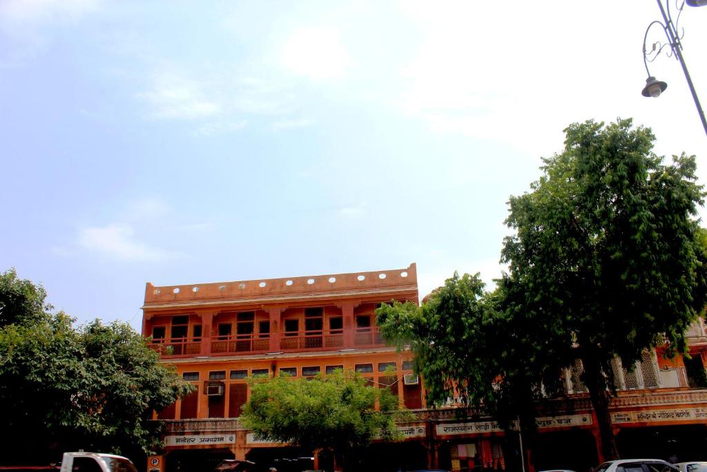 斋浦尔Friend India的一座红色的大建筑,前面有树木