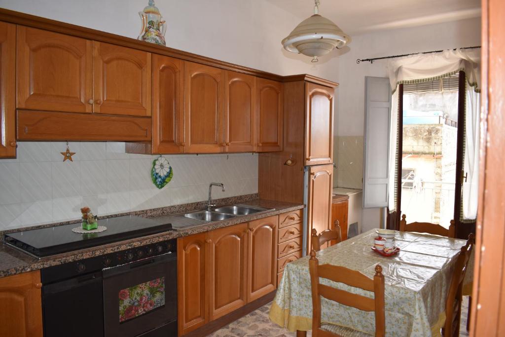 PietraperziaAppartamento ammobiliato的厨房配有木制橱柜、水槽和桌子