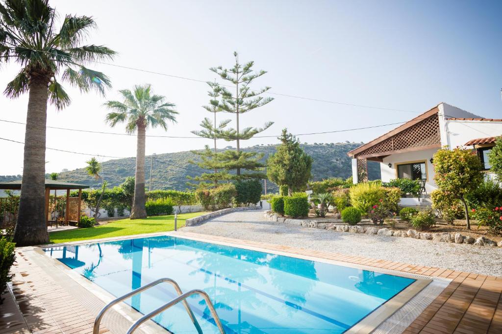 罗希姆诺Villa Metochi的一座棕榈树游泳池和一座房子