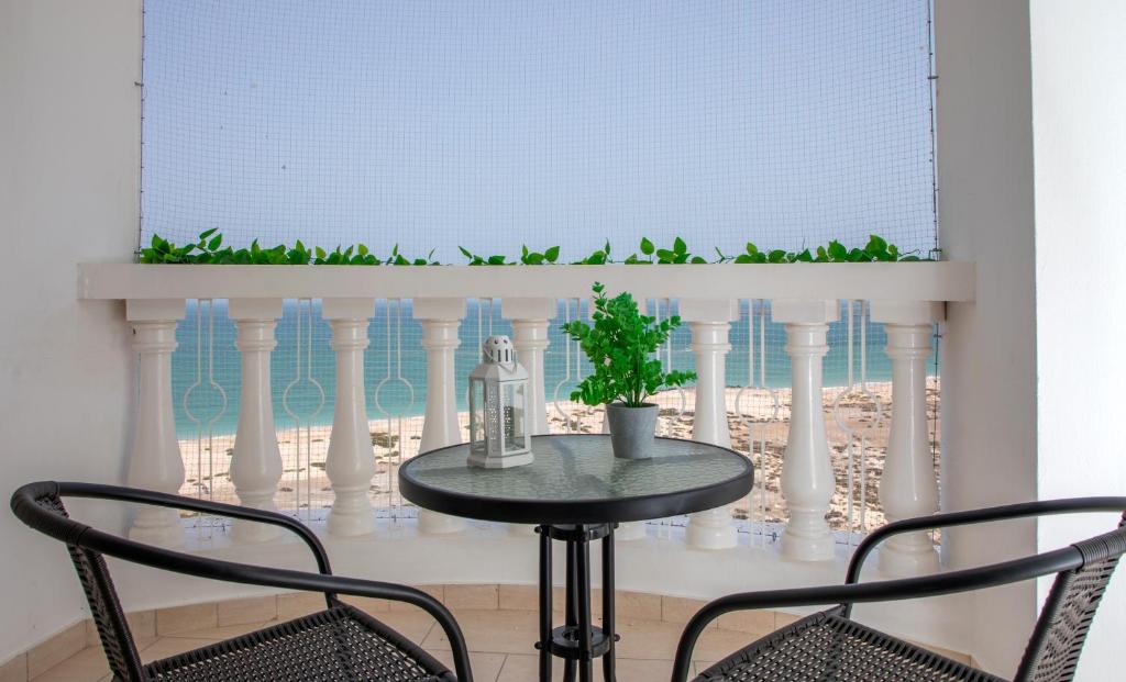拉斯阿尔卡麦Amazing sea view studio的桌子,两把椅子,窗户,桌子,植物