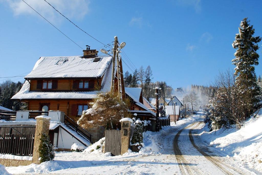 克雷尼察Adelka-dom przy stoku的火车站旁的一座房子,屋顶上有雪盖
