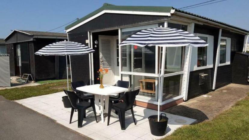 米德尔克尔克Vacation house MAX for 4 persons, 350 m from the sea, in Pollentier Middelkerke Park的一个带桌子和两把遮阳伞的庭院