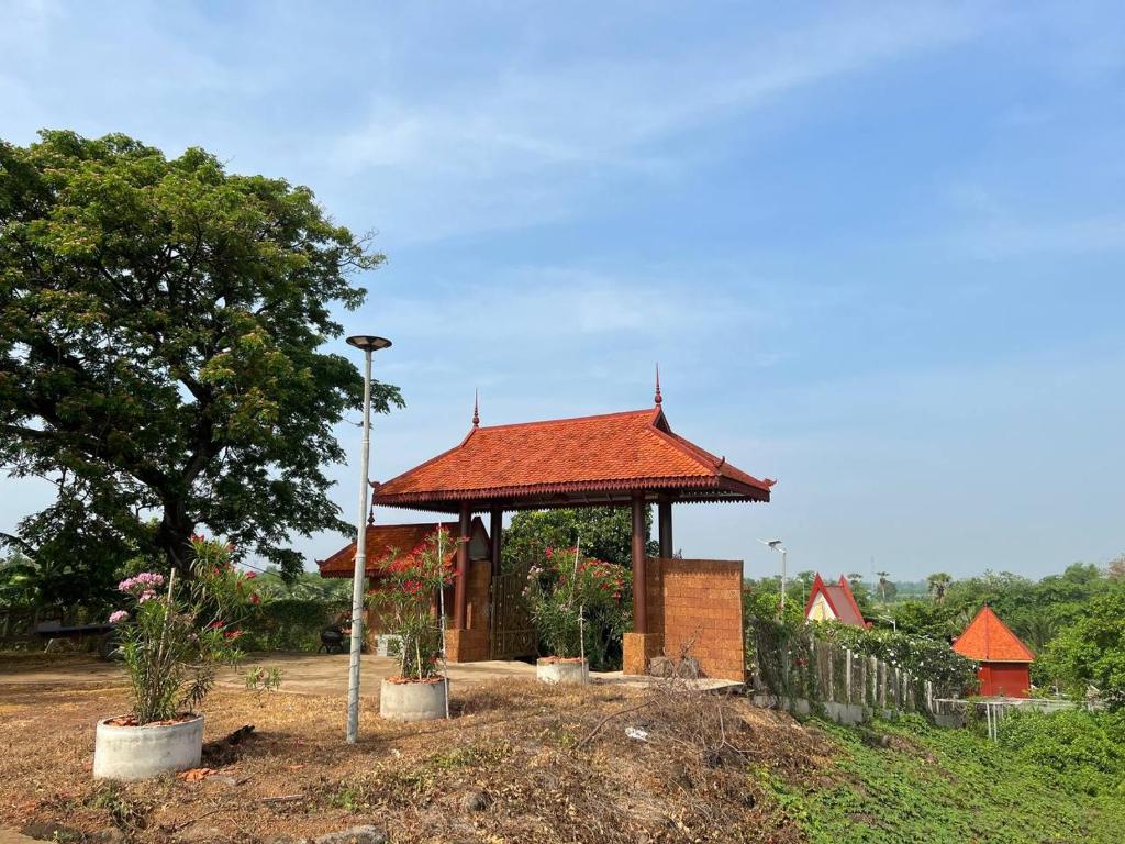 磅湛Toek Chha Temple Resort的田野上带红色屋顶的凉亭