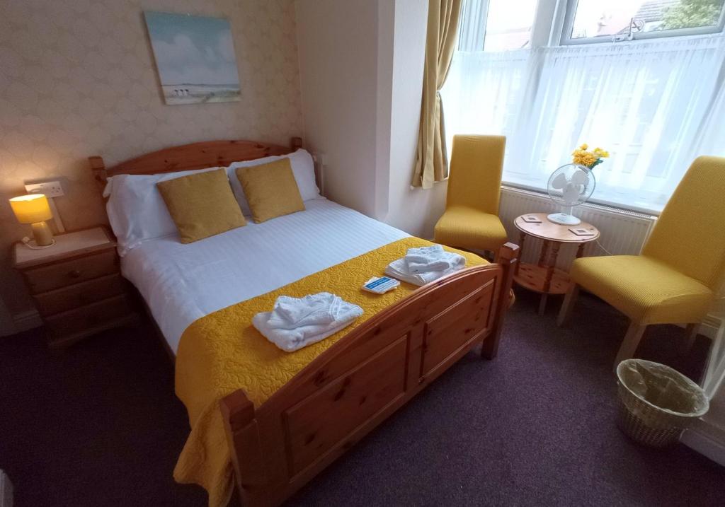 斯凯格内斯Brackenhurst Guest House的一间卧室配有一张大床和两张黄色椅子