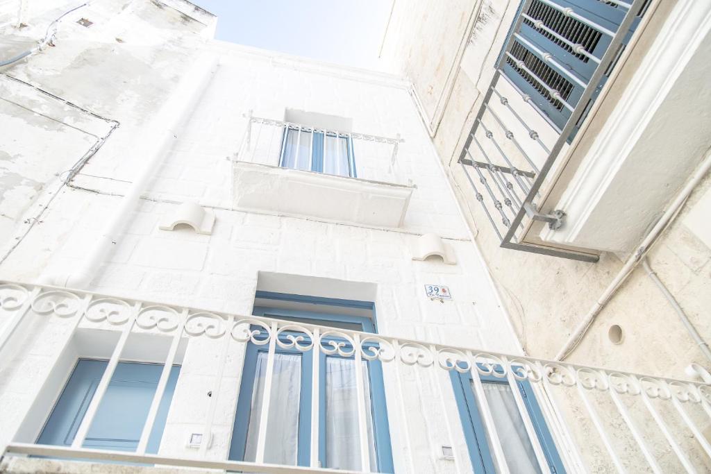 莫诺波利Borgo Albergo Capozzi 39的白色的建筑,设有蓝色的窗户和阳台