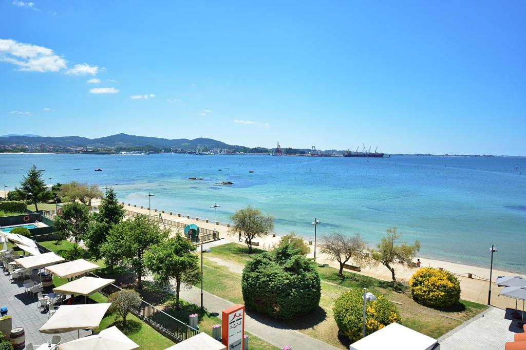 维拉加尔西亚·德·阿劳萨Ático con terraza y vistas al mar en Vilagarcía的享有海滩和大海的美景,配有遮阳伞