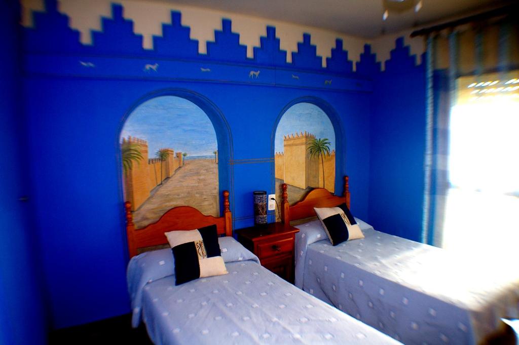 莱佩Pensión El Alamo的蓝色墙壁客房的两张床