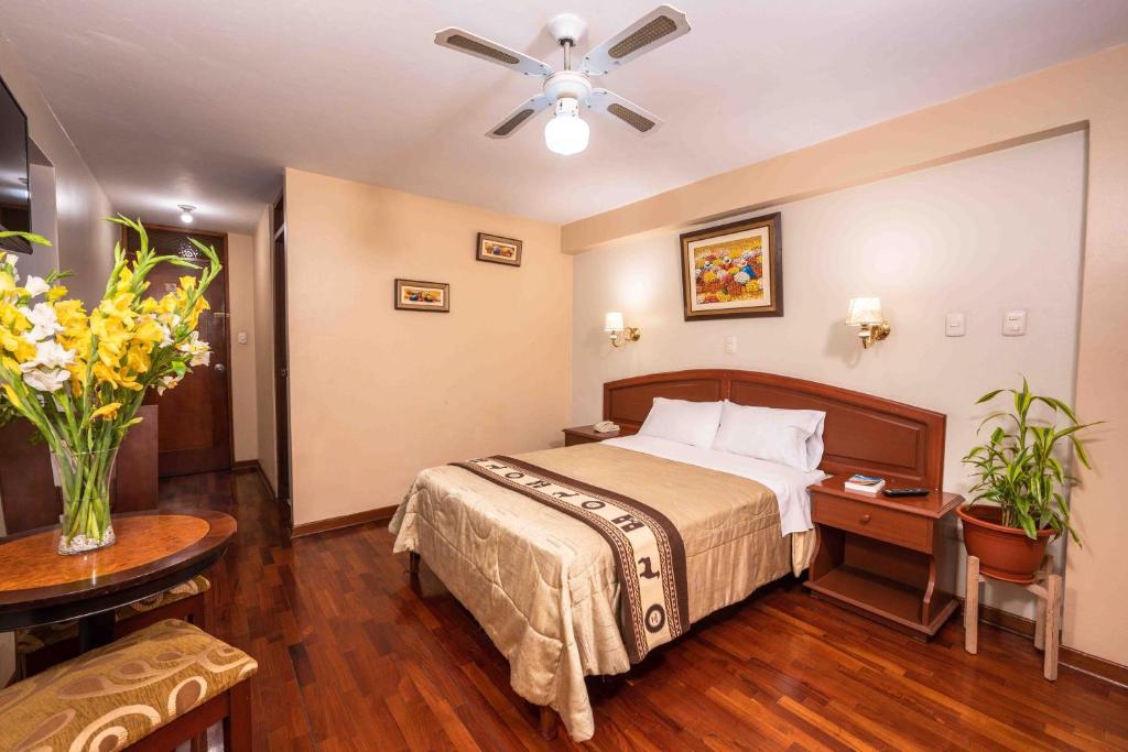 利马Hotel Manhattan Inn Airport的酒店客房配有一张床铺和一张桌子。