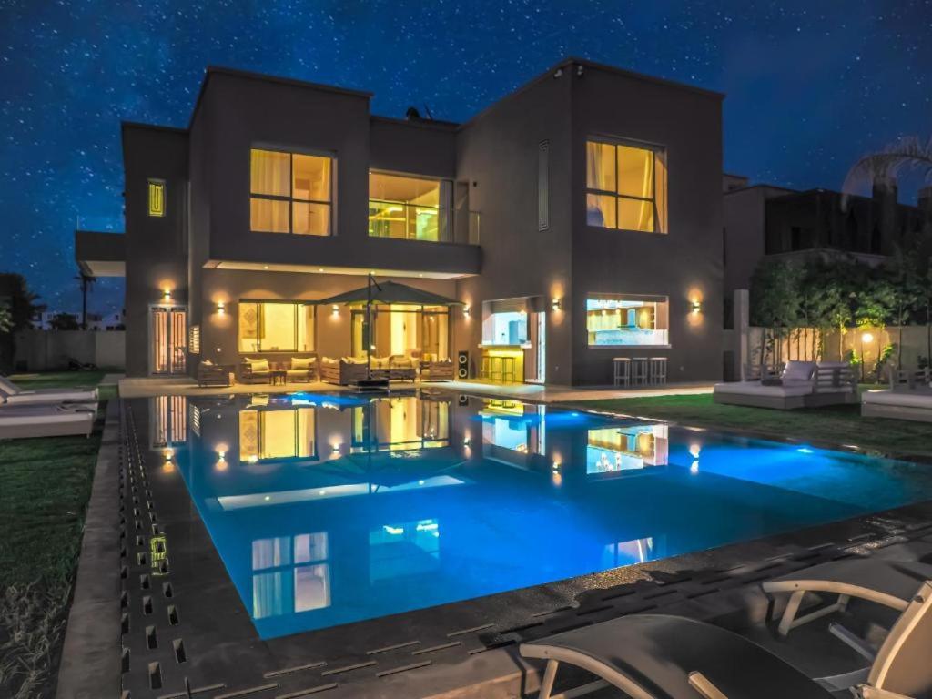 马拉喀什Villa Emraulde的一座晚上设有游泳池的房子
