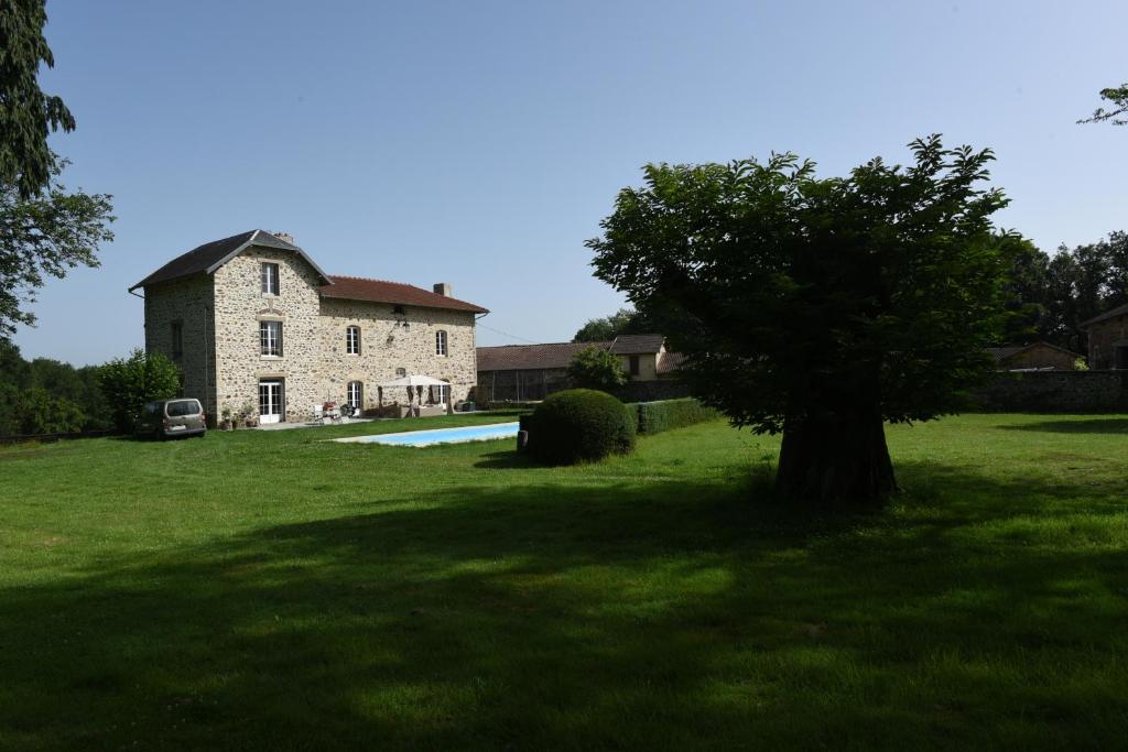圣莱奥纳尔德诺布拉Chambres d'hôtes La Babinerie的院子中一座大石头房子,有一棵树