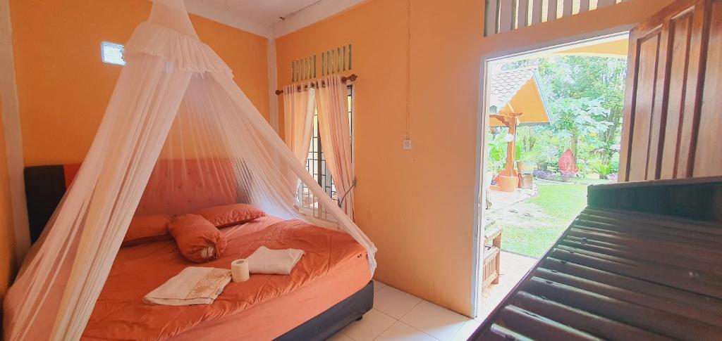 武吉拉旺Sumatra Cheeky Monkeys的窗户客房内的一张带蚊帐的床