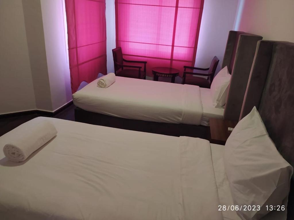 塞拉莱Salalah Beach Villas的配有粉红色照明的酒店客房内的两张床