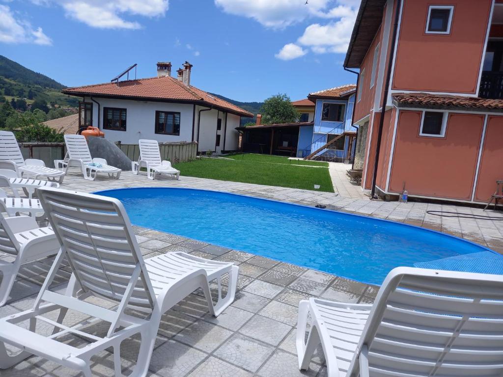 科普里夫什迪察Kъща за гости Демария的房屋旁的游泳池,带白色椅子
