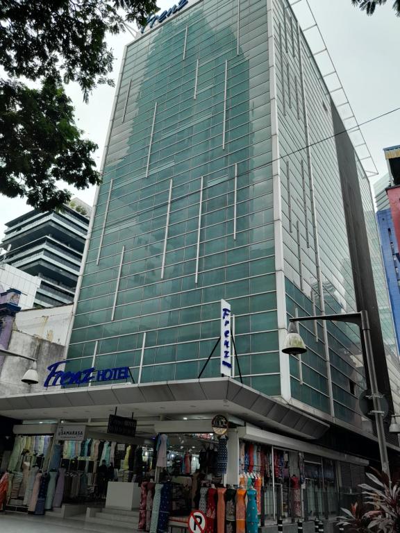 吉隆坡吉隆坡弗仁兹酒店的一座高大的玻璃建筑,前面有一间商店