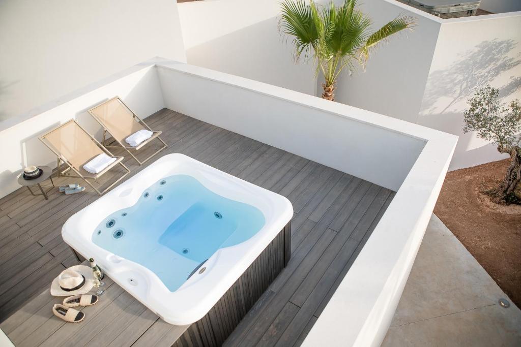 伊维萨镇Can Jaume Private Villas by Ocean Drive的浴室设有浴缸、两把椅子和一棵棕榈树