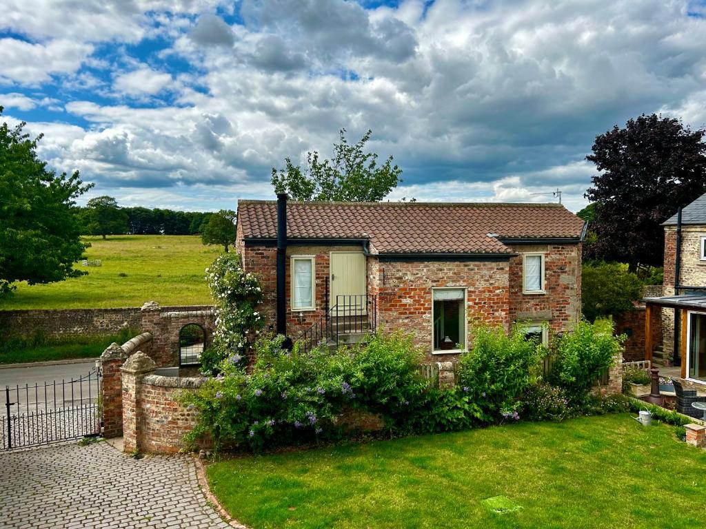 约克Tanyard Cottage - Whixley, York, North Yorkshire的庭院里带花园的砖房