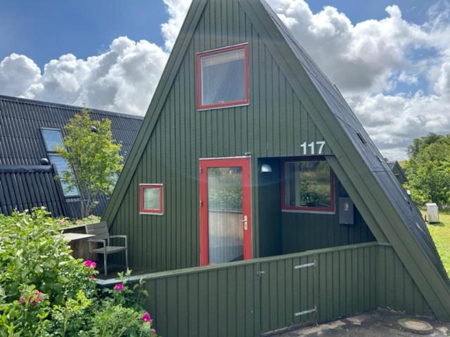 FarsøNice holiday home in beautiful resort的绿色的房子,有红色的门和窗户