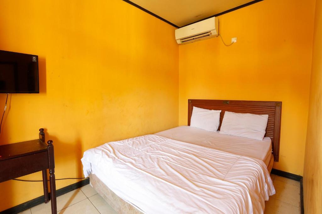 打拉根SPOT ON 92782 Rumah Kost Kita Tarakan的黄色墙的房间里一张床位