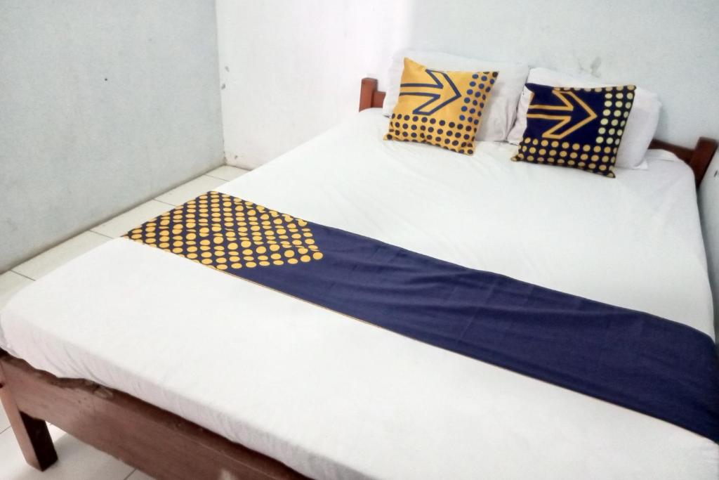 NgadipuroSPOT ON 92743 Kost Elisabeth Syariah的两张床铺,配有蓝色和黄色枕头