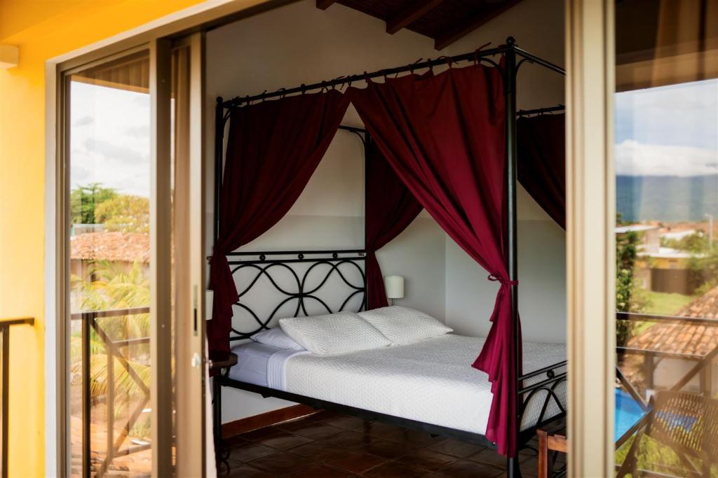 格拉纳达Hotel Jardín Garden de Granada Nicaragua的卧室设有一张位于阳台的天蓬床