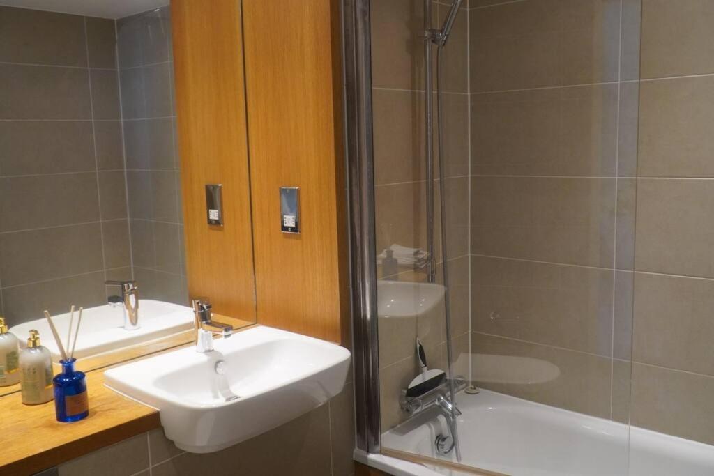 伦敦Tee SweetLux Apartment的浴室配有水槽、淋浴和浴缸。