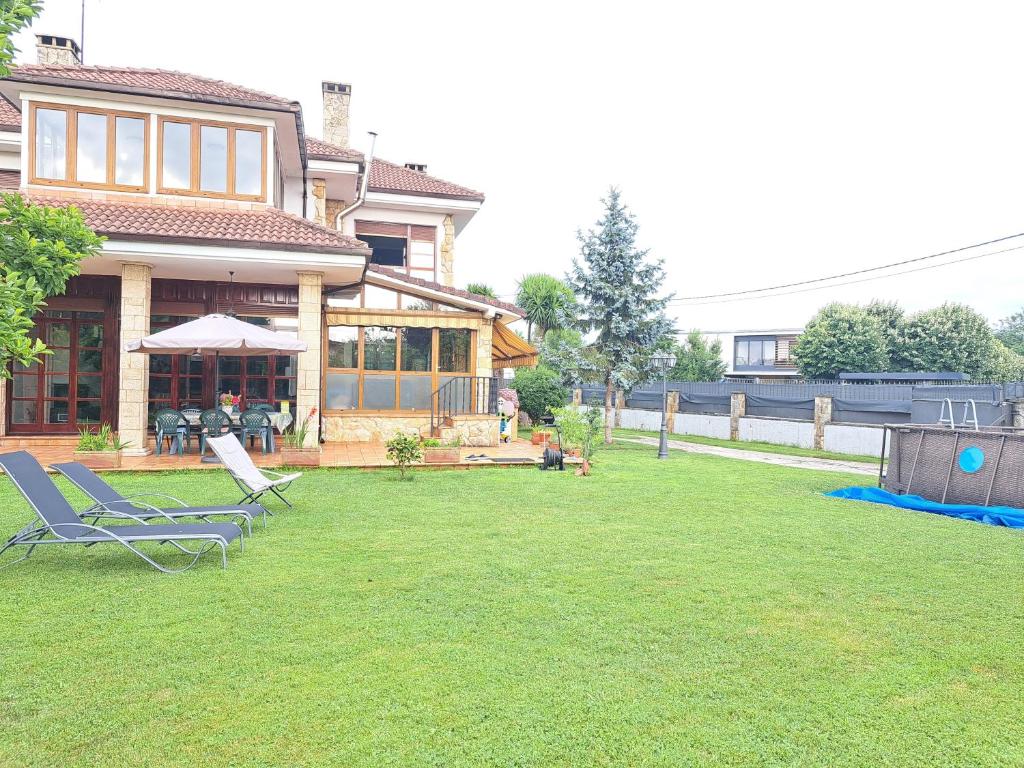希洪Casa Chalet, Villa Elisa的一个带两把草坪椅的院子和房子
