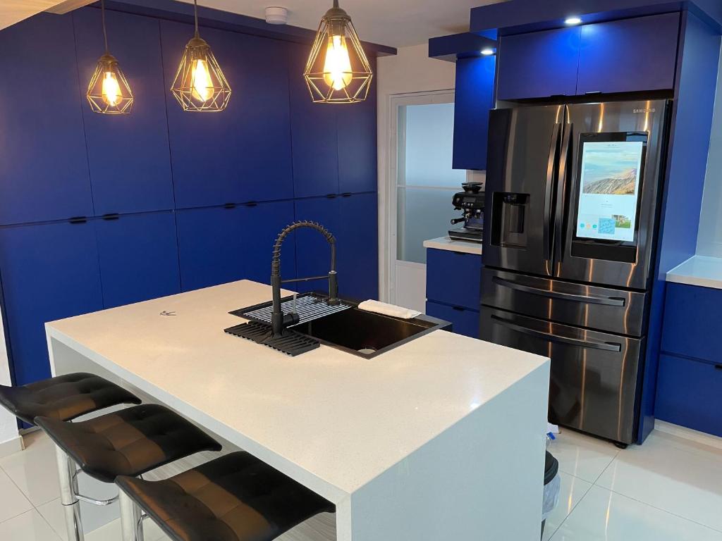 卢基约Luquillo Mar Paradise的一间设有蓝色橱柜的厨房和一个带冰箱的厨房岛