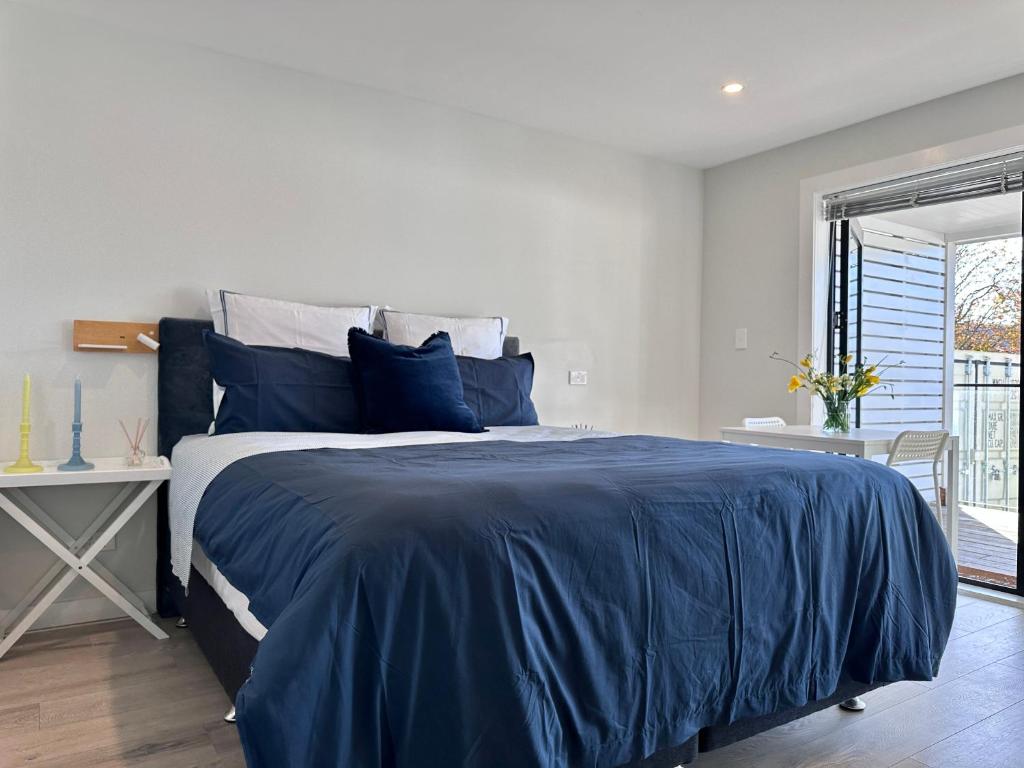 奥克兰66 Express luxury apartment in New Market Our apartments has Self-checkin System的一间卧室设有蓝色的床和窗户。