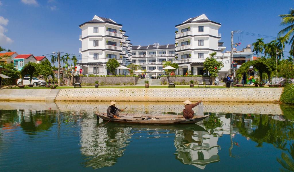 会安Gem Riverside Hotel Hoi An的两人在水中,有建筑物