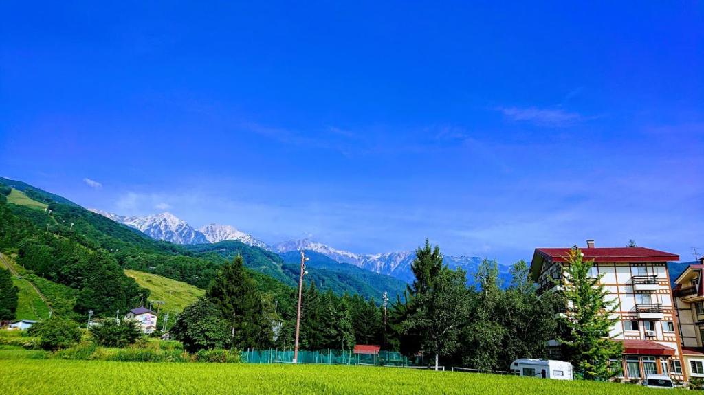 白马村罗森海姆哈库巴酒店的山丘上的建筑,背景是山脉