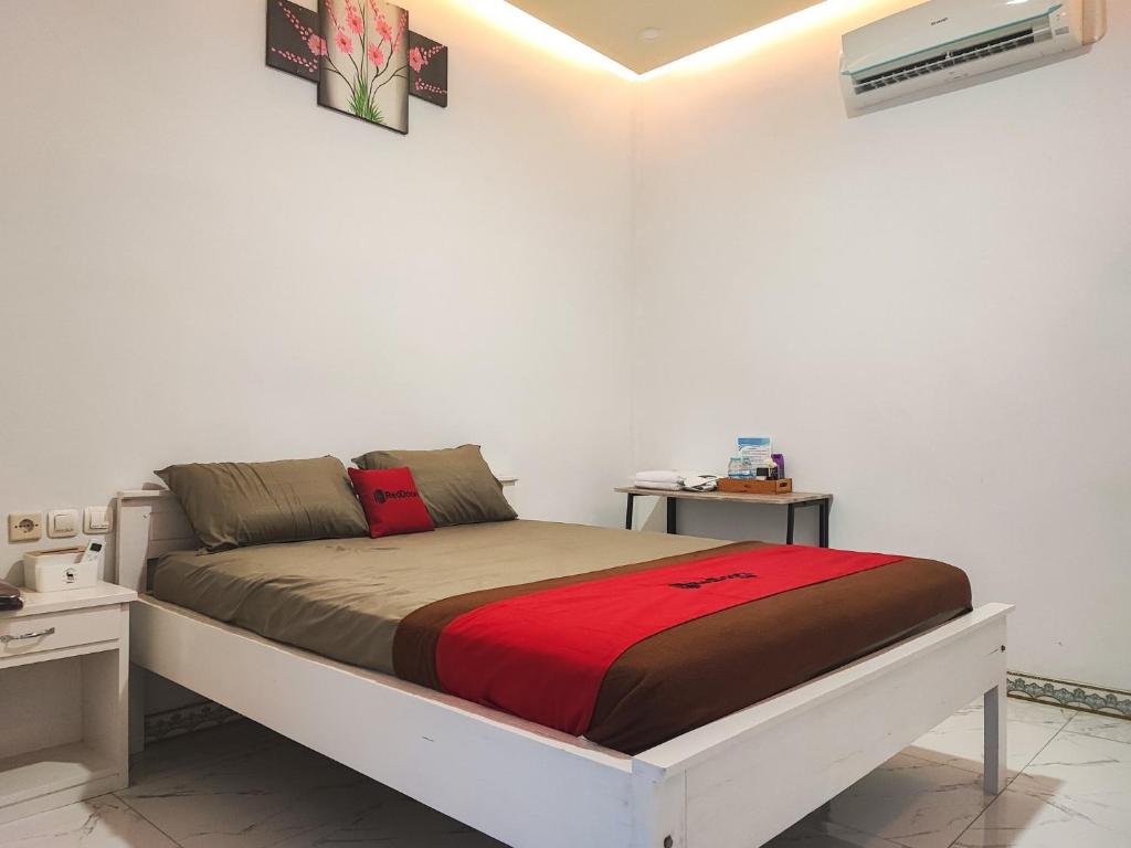 SarolangunRedDoorz Syariah at Naffa Homestay的白色房间的一个床位,有2个床头柜