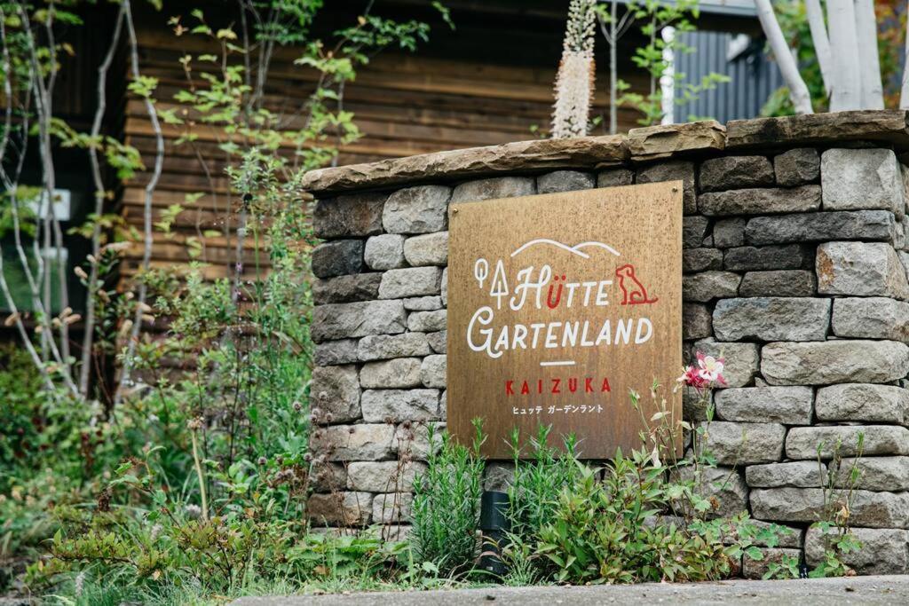 轻井泽Hutte Gartenland -KAIZUKA- ヒュッテ ガーテンラント カイヅカ的花园中石墙上的标志