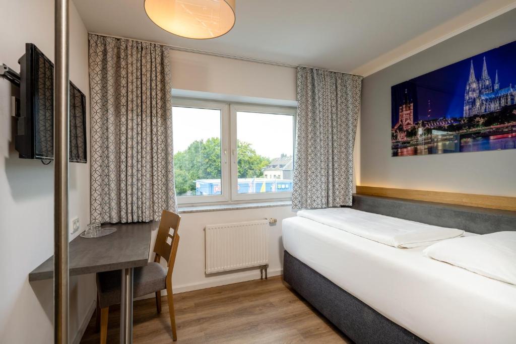 科隆特里顿酒店的一间卧室配有一张床、一张书桌和一个窗户。