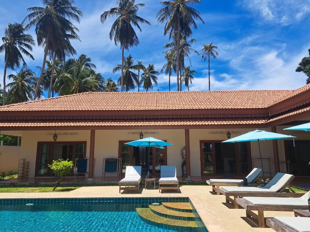 拉迈Laura Guest House Samui的一个带椅子和遮阳伞的游泳池的度假酒店