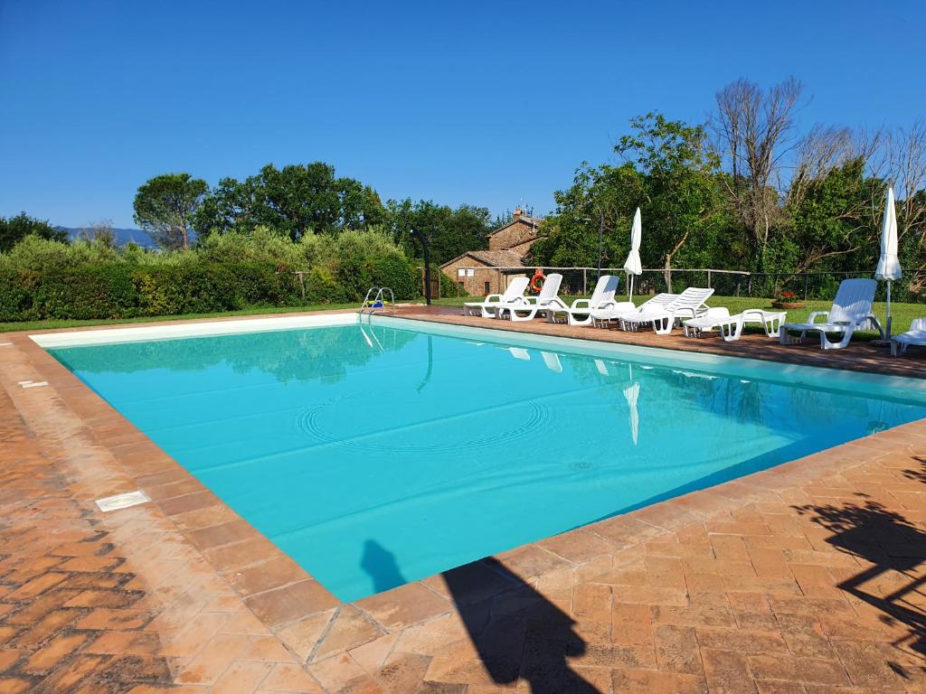 ProcenoAgriturismo POGGIO PORSENNA - con piscina的一座蓝色海水和椅子的大型游泳池